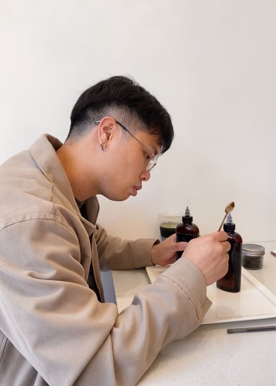 Photo of Chun Hwang sitting at a desk examining scientific lab equipment. 